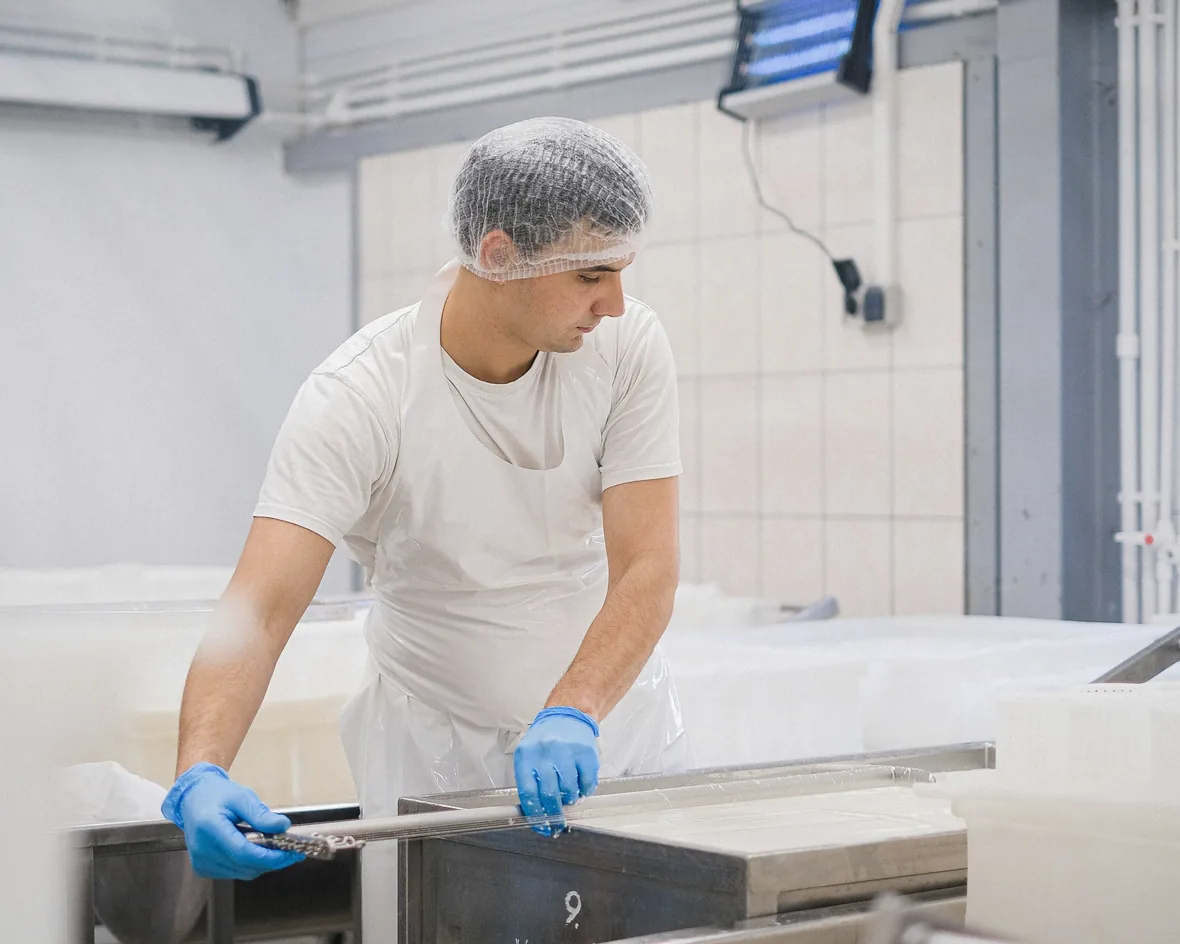 Operatore con cuffia e guanti al lavoro in un reparto alimentare