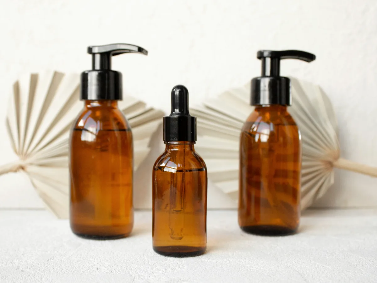 Three amber bottles with pump and dropper caps